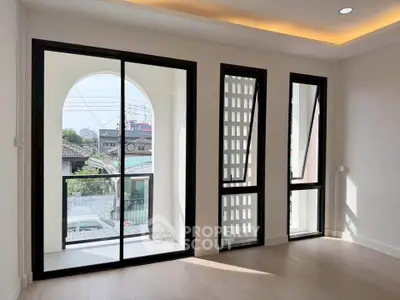 Bright modern room with large windows and balcony access, featuring sleek design and ample natural light.
