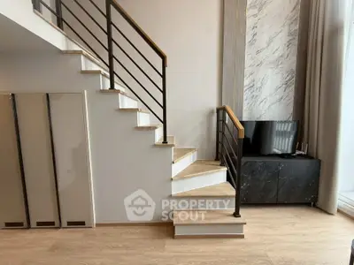 Modern interior with stylish staircase and sleek TV console in a contemporary living space.