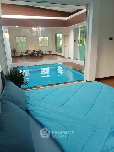 Luxurious indoor pool view from a cozy bedroom with modern decor and large windows.