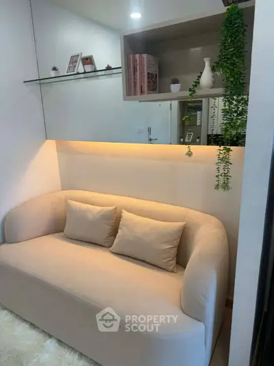 Cozy living room with modern beige sofa and decorative shelving, perfect for relaxation.