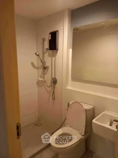Compact bathroom with shower, toilet, and sink in modern apartment.