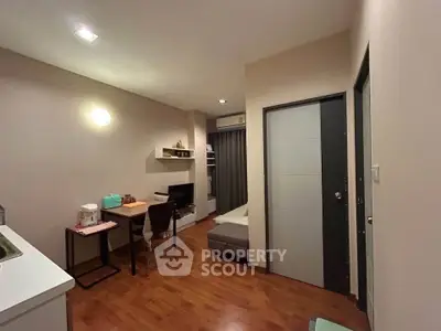 Cozy studio apartment with modern decor and wooden flooring, featuring a compact living area and study space.