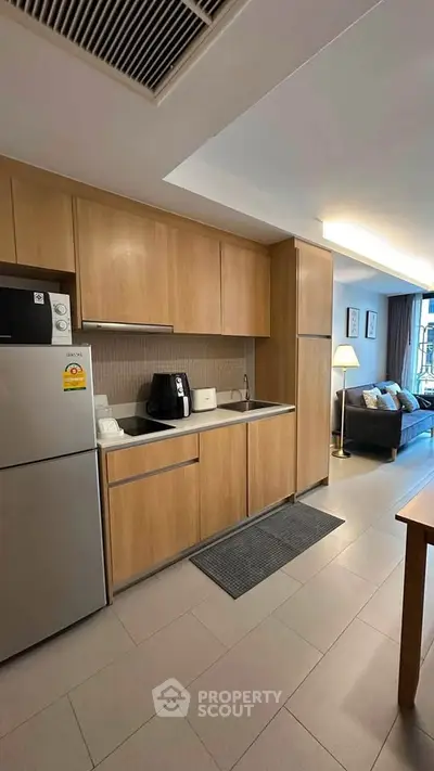 Modern kitchen with sleek wooden cabinets and stainless steel appliances in open layout apartment.