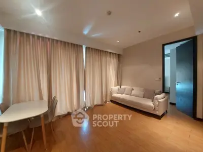 Spacious living room with cozy sofa and dining area, featuring elegant wooden flooring and soft lighting.