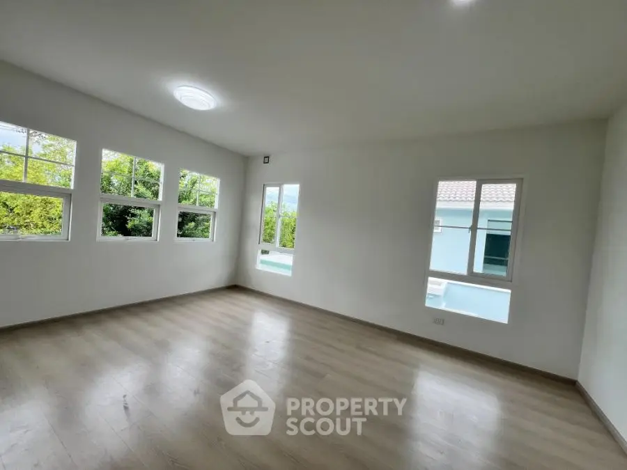 Spacious empty room with large windows and wooden flooring, perfect for customization.