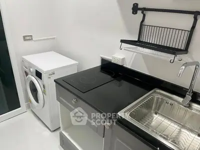 Modern kitchen with sleek black countertop and built-in appliances, featuring a washing machine and electric stove.