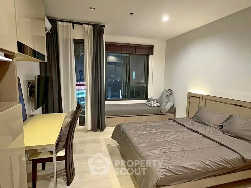 Modern bedroom with sleek design, featuring a cozy bed, study desk, and large window with city view.