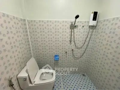 Compact bathroom with tiled walls and floor, featuring a toilet and shower area.