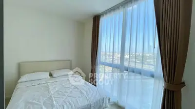 Bright bedroom with large window offering stunning city views and elegant curtains.