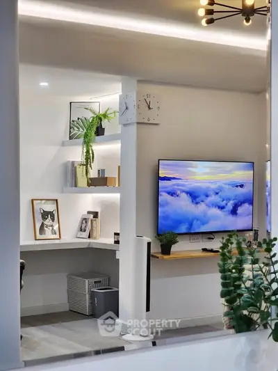 Modern living room with stylish decor and wall-mounted TV, featuring a cozy study nook.