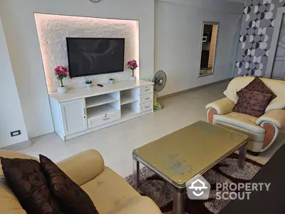 Elegant living room with plush seating and modern entertainment unit, accented by decorative lighting and stylish patterns.