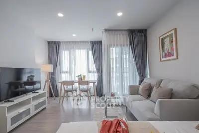 Modern living room with stylish decor and natural light, featuring a cozy sofa and dining area.
