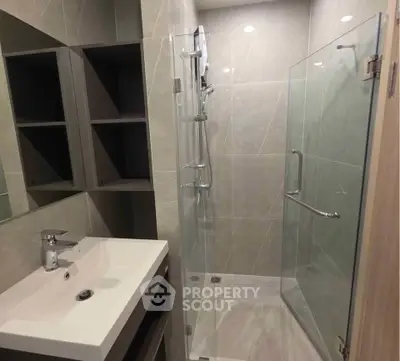 Modern bathroom with glass shower and sleek sink in contemporary apartment.