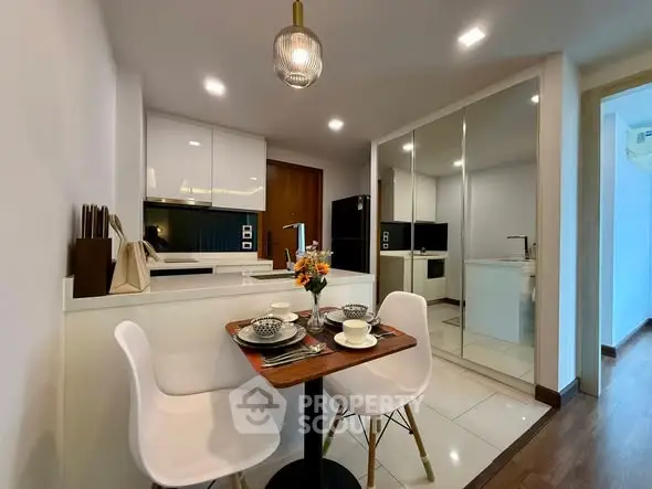 Modern kitchen with dining area, sleek cabinetry, and mirrored storage.