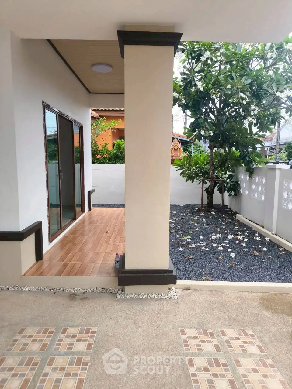 Charming outdoor patio with tiled flooring and lush garden view, perfect for relaxation and entertaining.