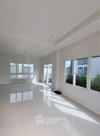 Spacious and bright living room with large windows and glossy floors