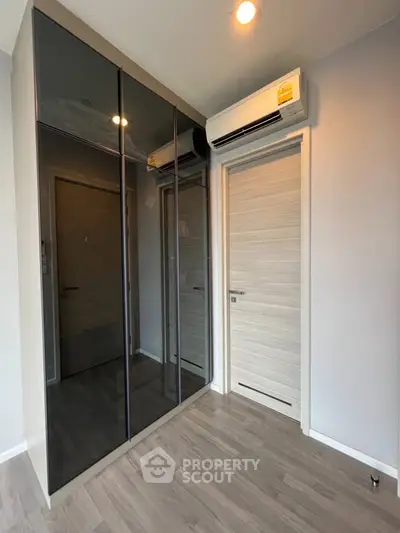 Modern bedroom with sleek mirrored wardrobe and air conditioning unit