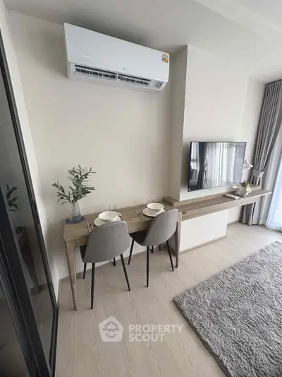 Modern living room with air conditioning, dining setup, and TV, featuring sleek furniture and natural light.