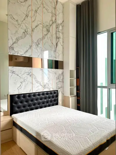 Modern bedroom with stylish marble accent wall and large window for natural light.