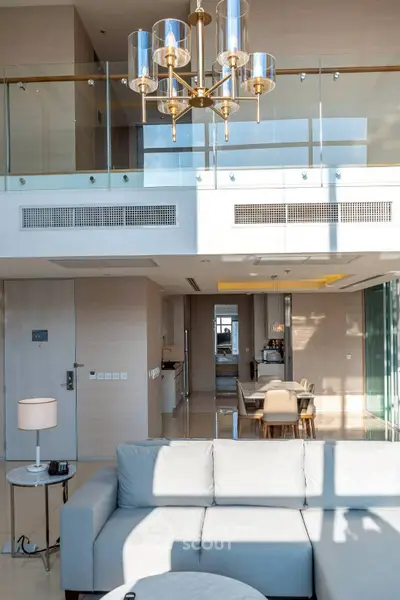 Luxurious modern living room with high ceilings and elegant chandelier in a spacious open-plan apartment.