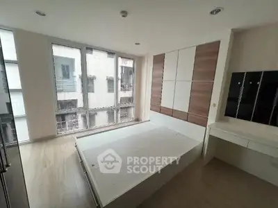 Modern bedroom with large windows and built-in wardrobe in a stylish apartment.