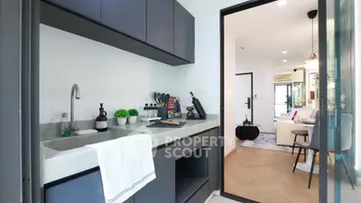 Modern kitchen with sleek cabinetry and open layout leading to stylish living room.
