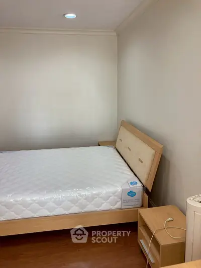 Cozy bedroom with wooden bed frame and nightstand, perfect for a minimalist lifestyle.