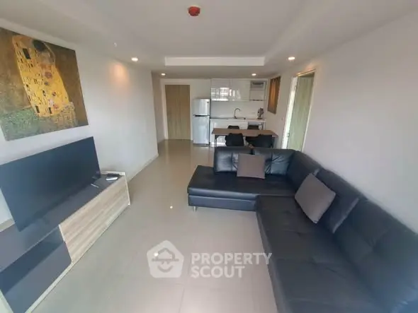 Modern living room with sleek black sofa and open kitchen layout in a stylish apartment.