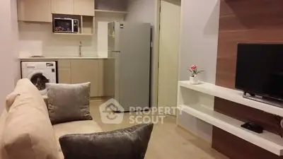 Modern living room with integrated kitchen featuring washing machine and fridge.