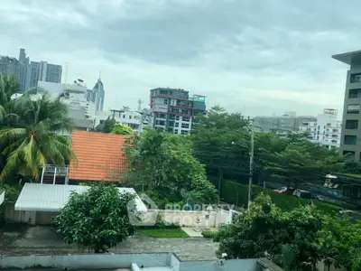 Stunning cityscape view from a high-rise apartment, showcasing lush greenery and modern architecture.