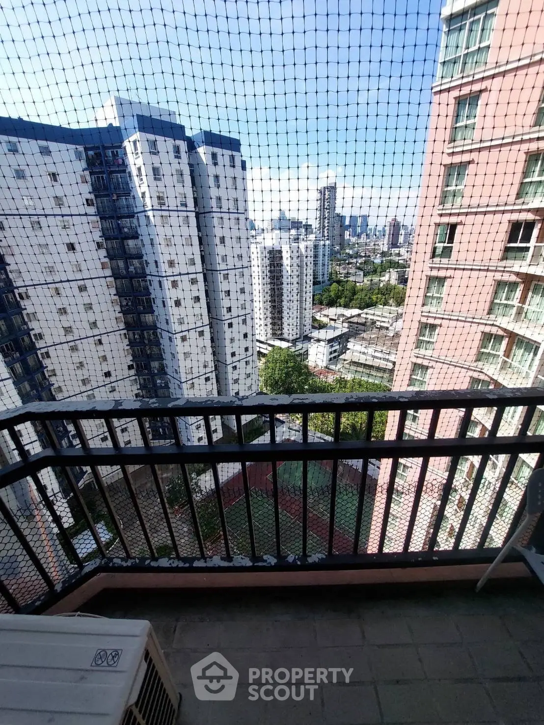 Stunning cityscape view from a high-rise balcony with safety netting, perfect for urban living.