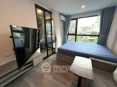 Modern bedroom with large windows and sleek TV setup in urban apartment.