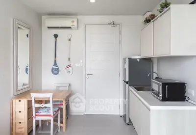 Modern kitchen with sleek cabinetry and compact dining area, featuring a microwave and fridge.