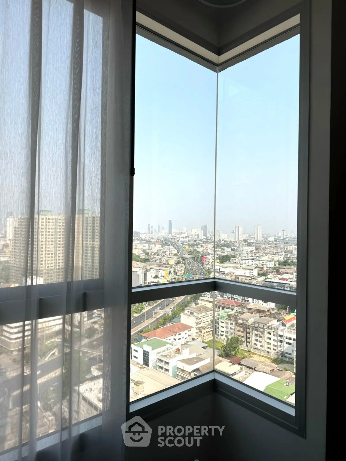 Stunning corner unit with panoramic city view from high-rise apartment window.