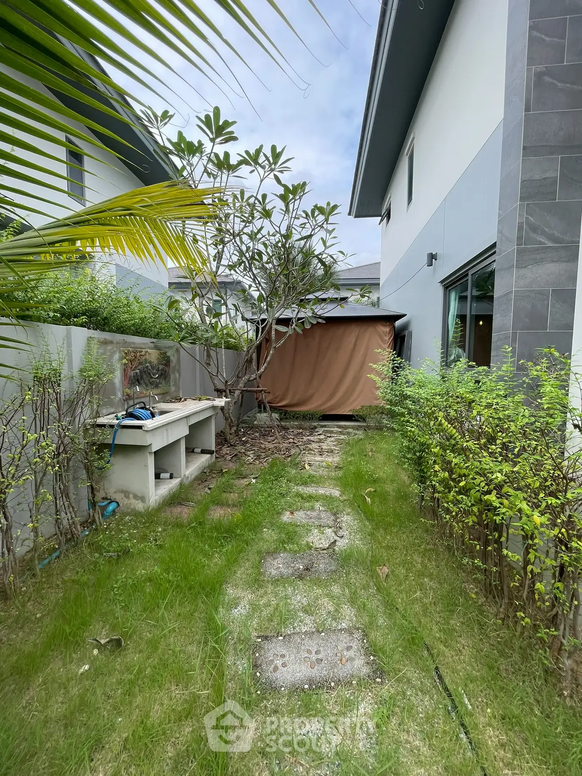 Charming garden pathway in modern residential property with lush greenery and privacy fence.