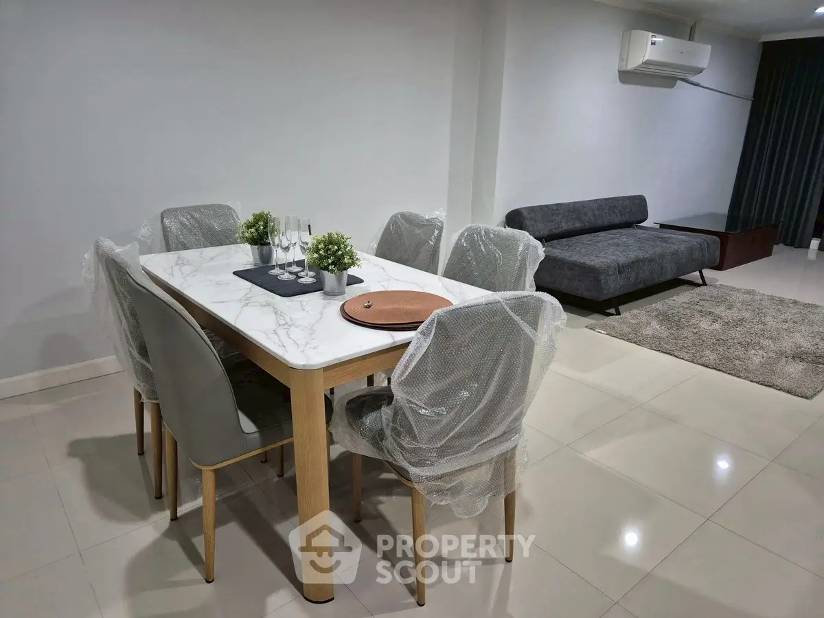 Modern dining area with marble table and stylish sofa in open living space.