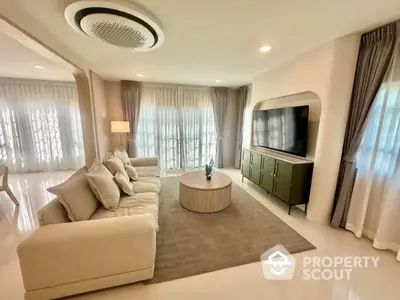 Elegant living room with modern decor and large windows, featuring a cozy sofa and stylish entertainment unit.