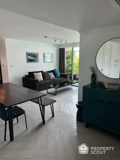 Modern living room with stylish decor and natural light, featuring a cozy sofa and elegant dining area.