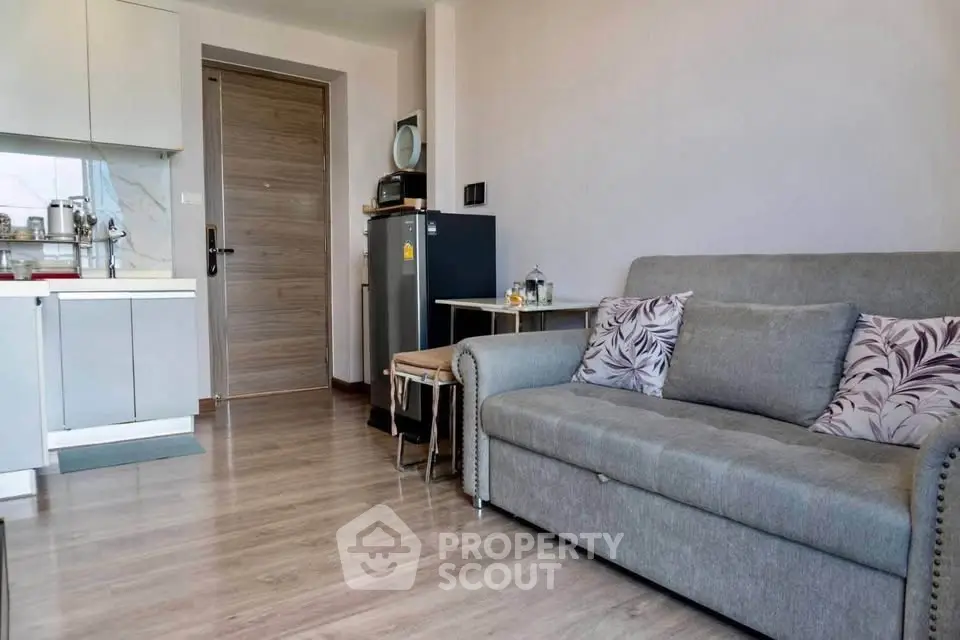 Modern living room with cozy sofa and compact kitchen in open layout apartment.