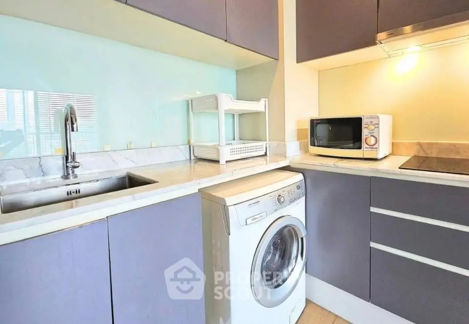 Modern kitchen with washing machine and microwave in sleek cabinetry