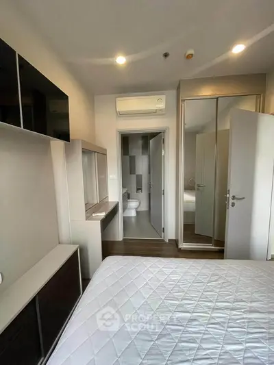 Modern bedroom with ensuite bathroom and mirrored closet doors in a stylish apartment.