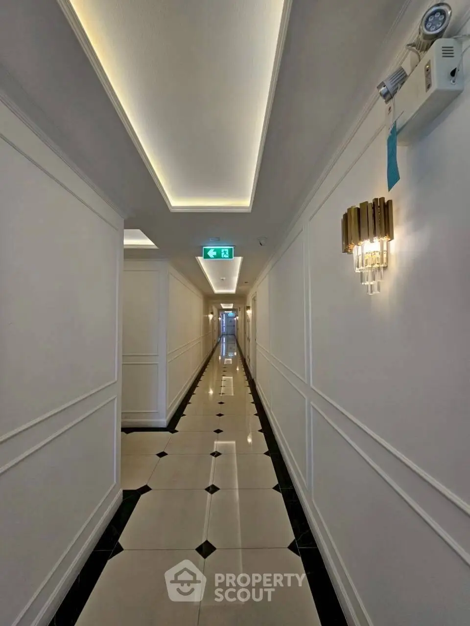 Elegant corridor with modern lighting and polished tile flooring in upscale building.