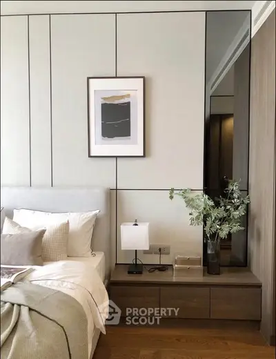 Elegant bedroom with modern decor, featuring a cozy bed, stylish nightstand, and framed artwork on the wall.