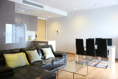Modern open-layout living room with sleek furniture and dining area, featuring hardwood floors and contemporary design.