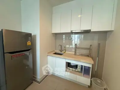 Modern compact kitchen with sleek white cabinets and stainless steel fridge