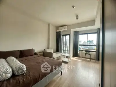 Spacious bedroom with city view and modern furnishings in a high-rise apartment.