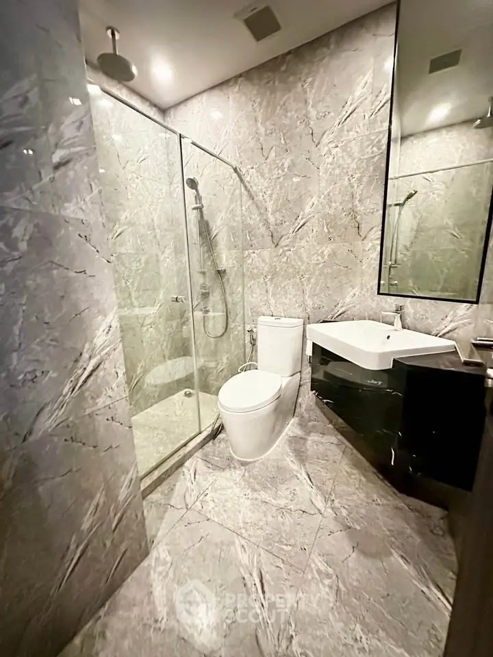 Luxurious marble bathroom with modern fixtures and glass shower enclosure.