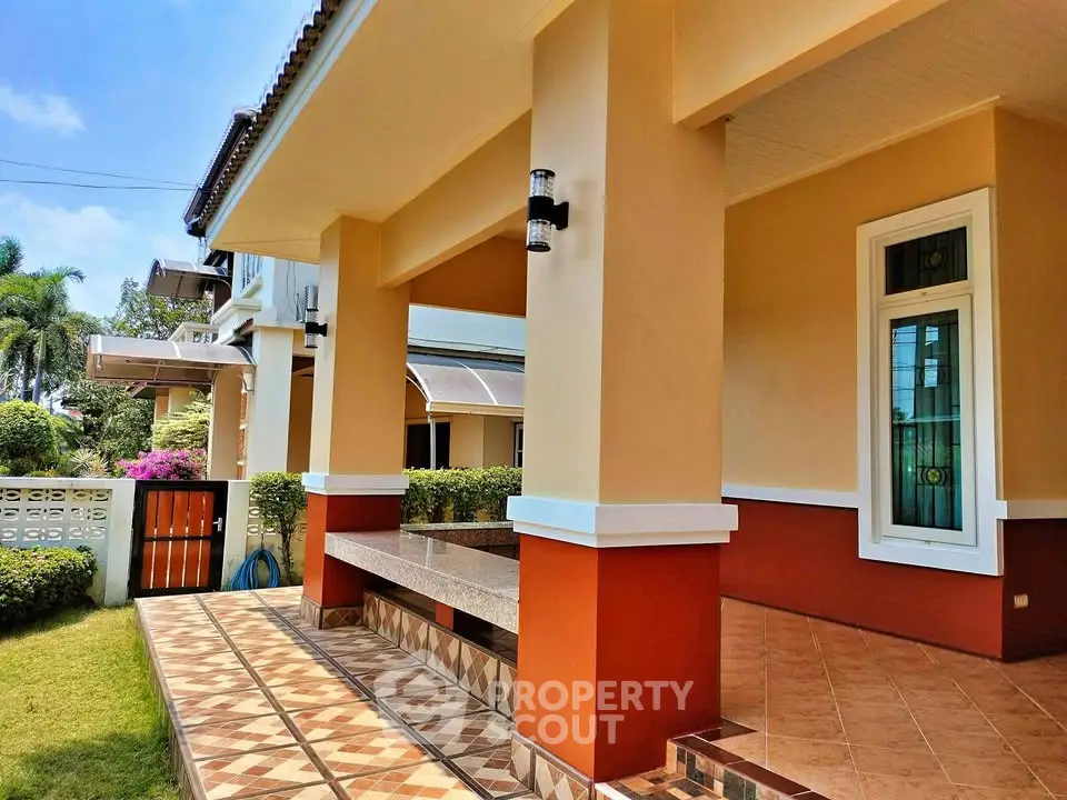Charming exterior view of a modern home with tiled porch and lush garden, perfect for relaxation and outdoor enjoyment.