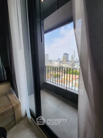 Stunning city view from modern apartment balcony with floor-to-ceiling windows and elegant curtains.