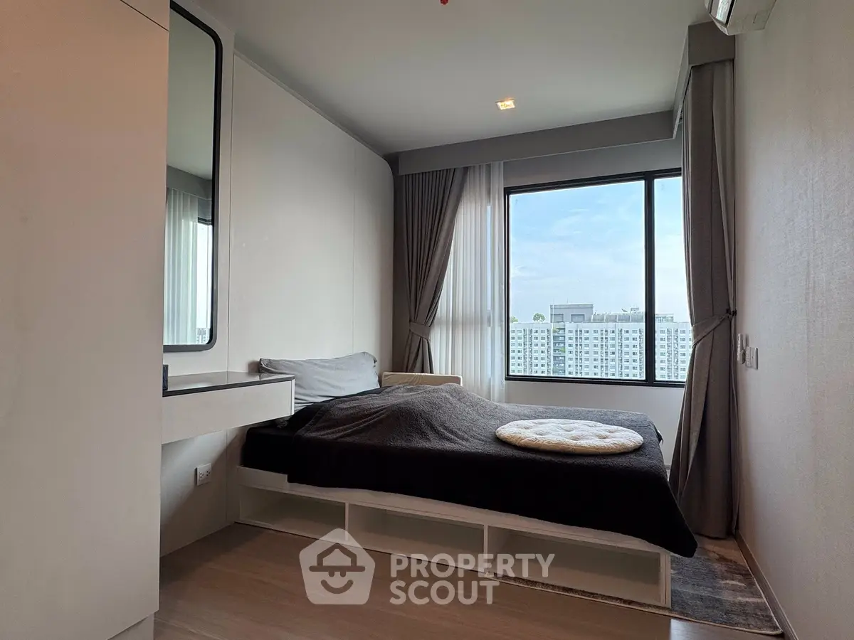 Modern bedroom with large window offering city view, featuring sleek design and cozy atmosphere.
